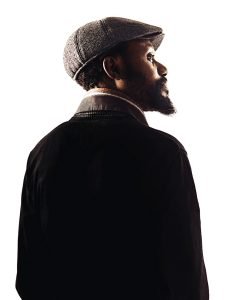 Portrait of a bearded elegant afro american man wearing a scarf and a cap. Sharp focus on eyes. Studio shot and white background. Sharp focus on eyes.